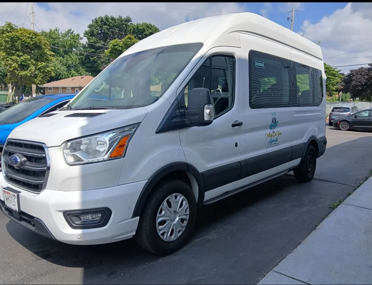 The What's On Your Agenda high-roof Ford Transit passenger van parked in Milwaukee.